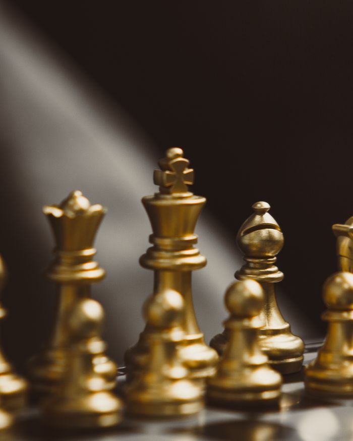 Bright and elegant golden chess pieces arranged on a chessboard, emphasizing strategic thinking and luxury.